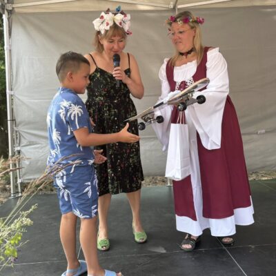 chłopczyk odbiera nagrodę-deskorolkę od kobiety na scenie