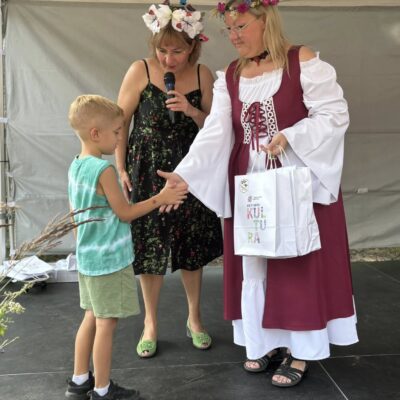 chłopczyk odbiera nagrodę od kobiety na scenie