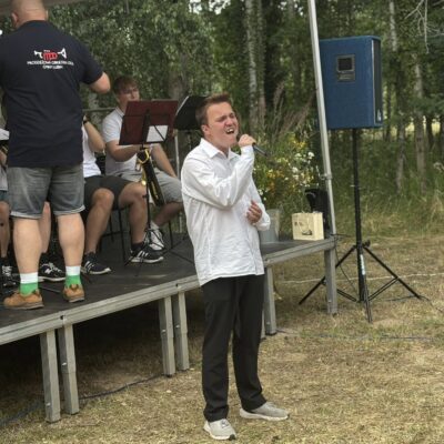 mężczyzna stoi przed sceną i śpiewa w tle gra orkiestra