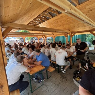 ludzie siedzą pod wiatą słuchają muzyki, piją i jedzą