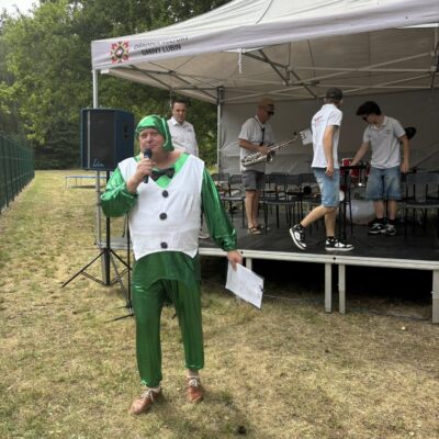 sołtys przemawia do mikrofonu w stroju konika polnego