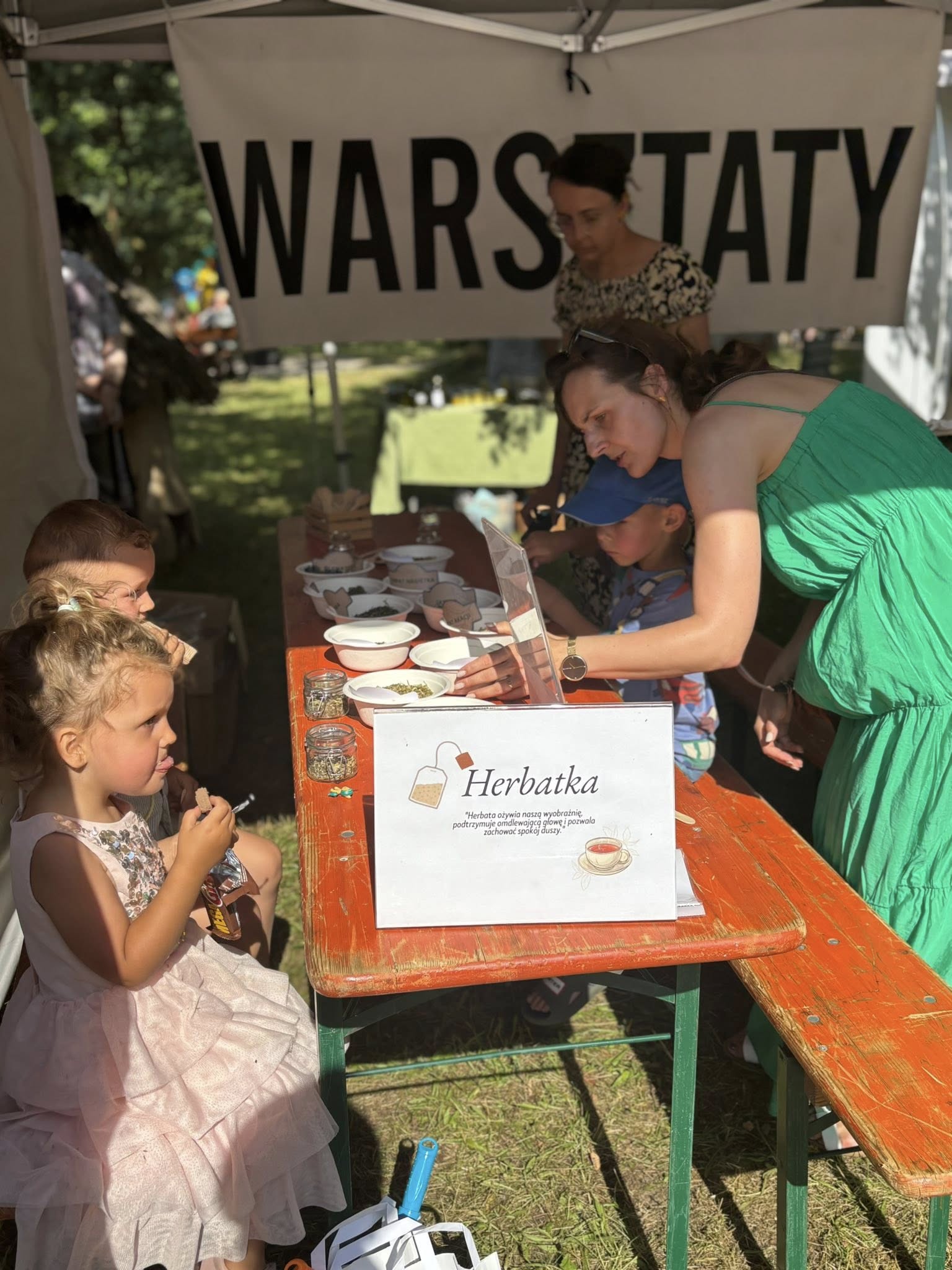 ludzie pod namiotem z warsztatami robią receptury herbat