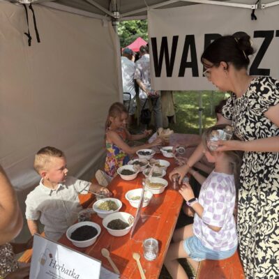 ludzie pod namiotem z warsztatami robią receptury herbat