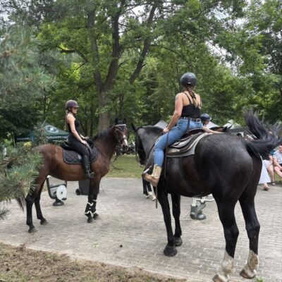 dwie kobiety na koniach w tle drzewa