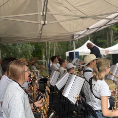 orkiestra na scenie gra na instrumentach dętych kapelmist w tle