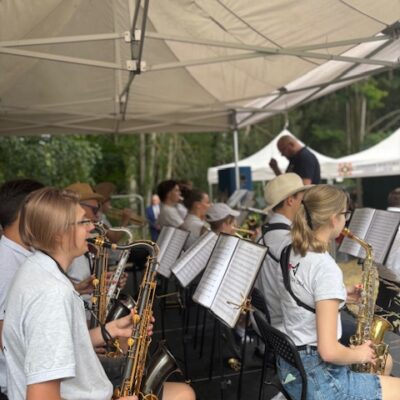 orkiestra na scenie gra na instrumentach dętych kapelmistrz w tle