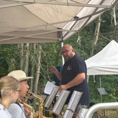 orkiestra na scenie gra na instrumentach dętych w tle kapelmistrz