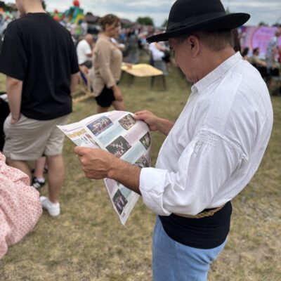 mężczyzna w kapeluszu ogląda gazetę kyczera