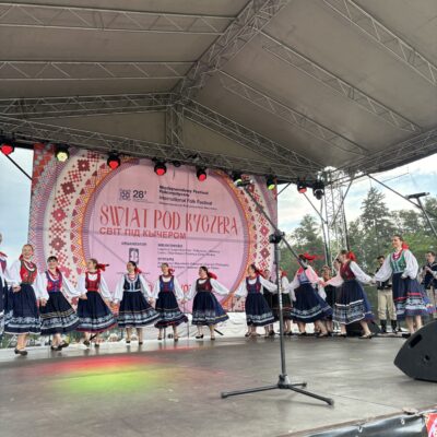 zespół na scenie tańczy w granatowo czerwonych sukniach