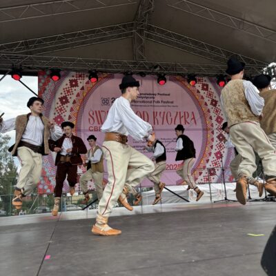 mężczyźni tańczą na scenie w kapeluszach