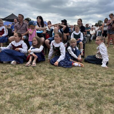 dzieci siedzą na trawie przed sceną