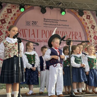 chłopczykz dziewczynką przy mikrofonie śpiewają w tle dzieci