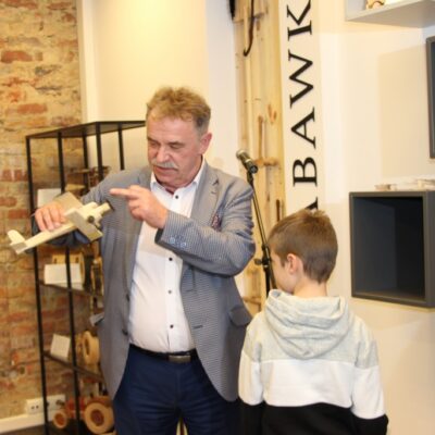 Tadeusz Kielan z chłopcem pokazuje mu drewniany samolot w muzeum zabawek