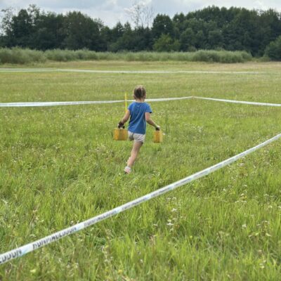 dziecko biegnie z obciążnikami na polu
