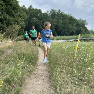 zawodnicy biegną w trasie w polu