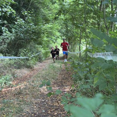 zawodnicy biegną na trasie w lesie