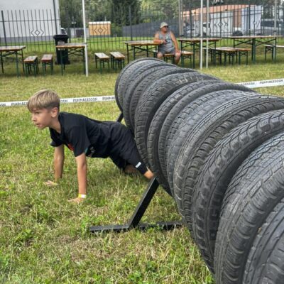 chłopiec wychodzi z pod przeszkody z oponami