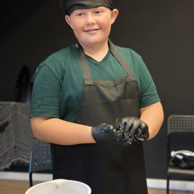 chłopiec w fartuchu opiera cebulę