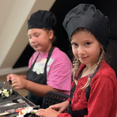 dziewczynka w fartuchu kroi sushi