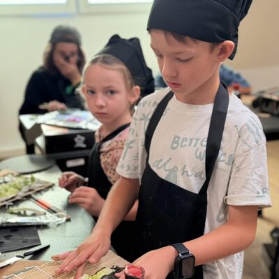chłopiec w fartuchu kroi sushi