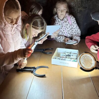dziewczynki oglądają kamienie i podziwiają przez lupę