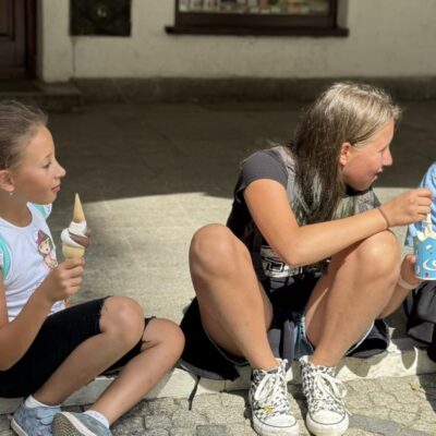 dwie dziewczynki jedzą lody na chodniku