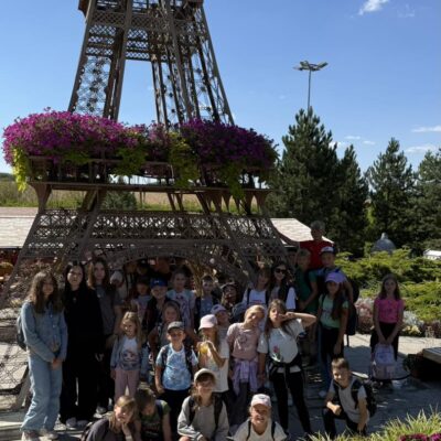 dzieci pozują do zdjęci przy wierzy ozdobionej kwiatami