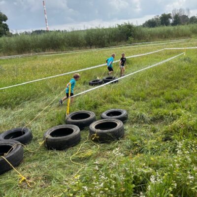 dziecko ciągnie oponę w polu