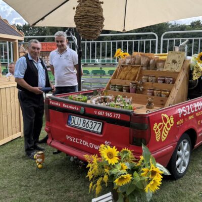 sprzedawca miodu przy swoim stoisku, auto z produktami