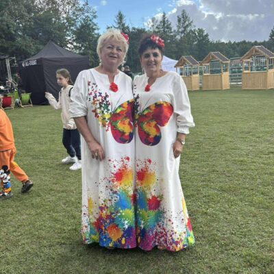 dwie kobiety pozują do zdjęcia w kolorowych sukniach