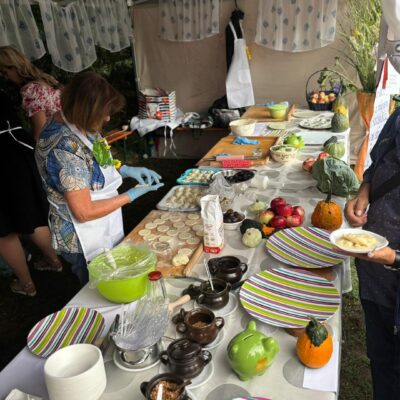 kobieta lepi pierogi przy długim stole