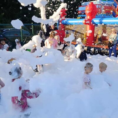 dzieci szaleją w piana party w tle dmuchańce