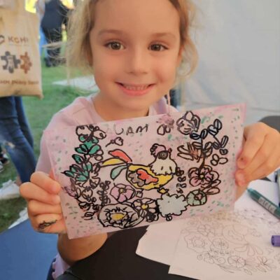 dziewczynka z pracą namalowaną na szkle pokazuje ją do zdjęcia